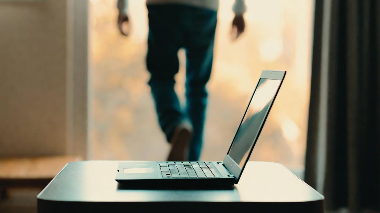 A laptop sitting open on a desk, running autonomously while its owner walks away
